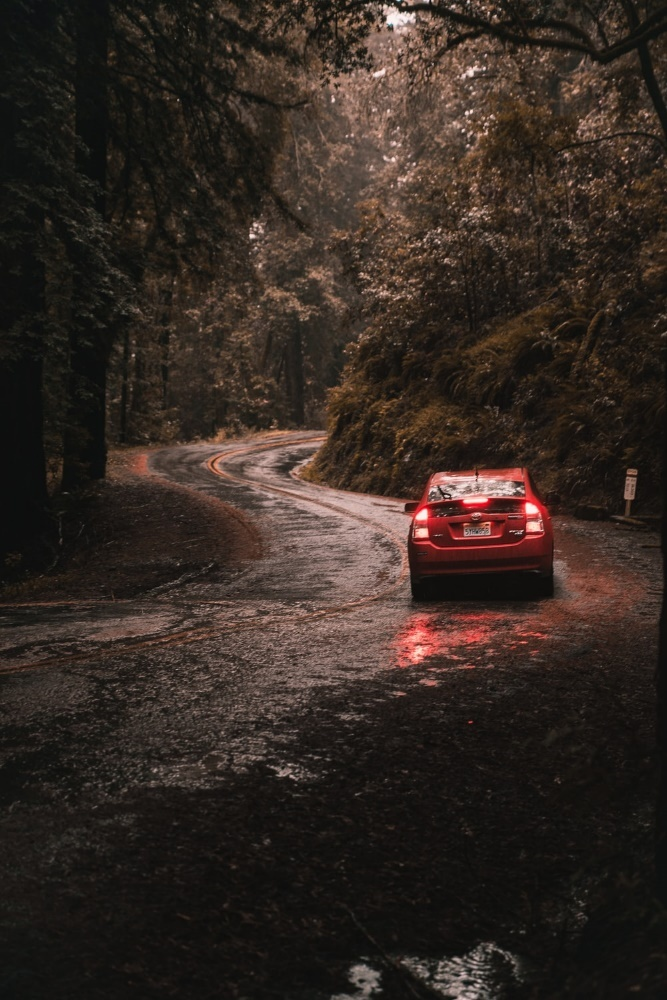 a red car driving through heavy rains.